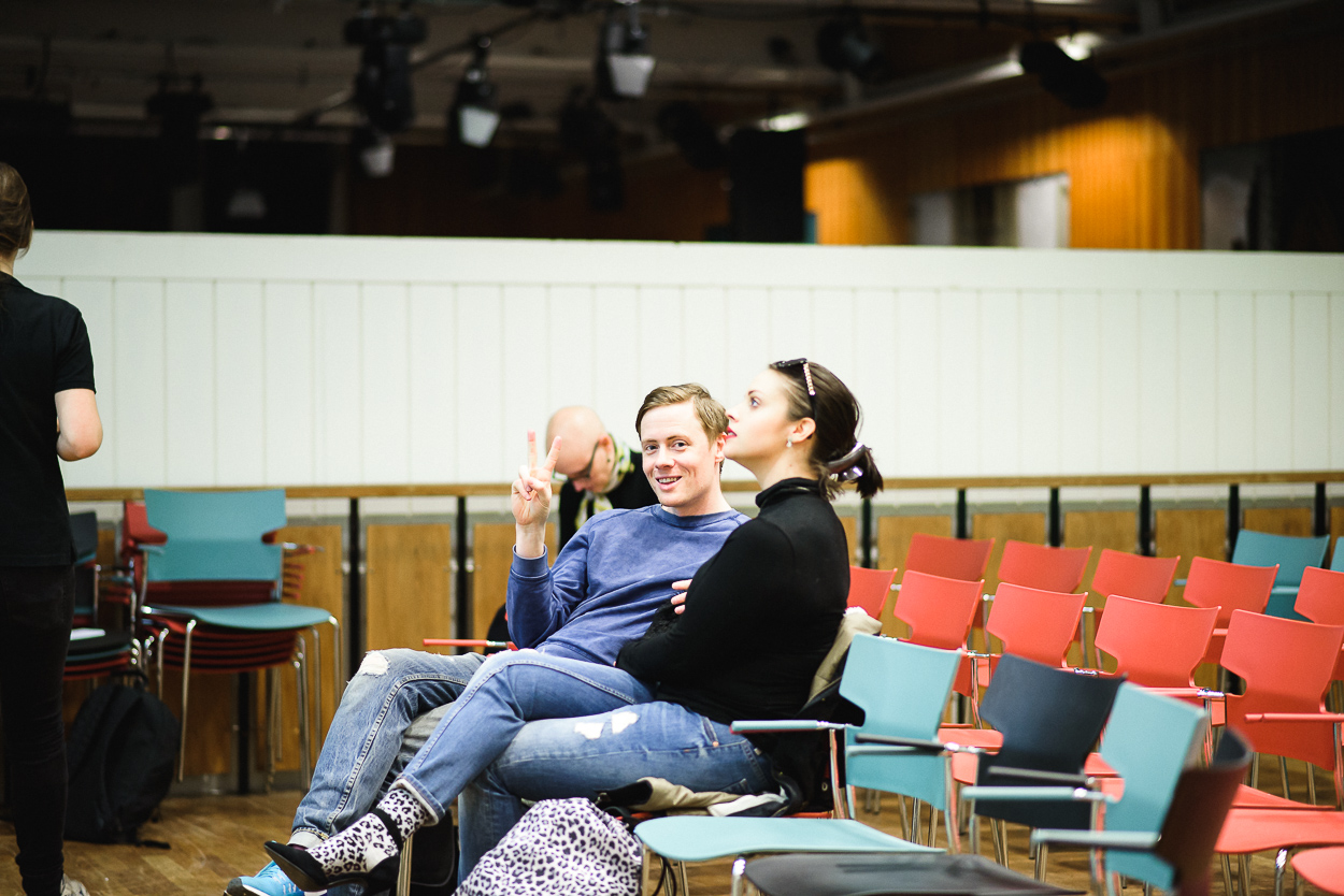 2 studenter som sitter i en föreläsningssal, en av dem kollar mot kameran och gör ett 