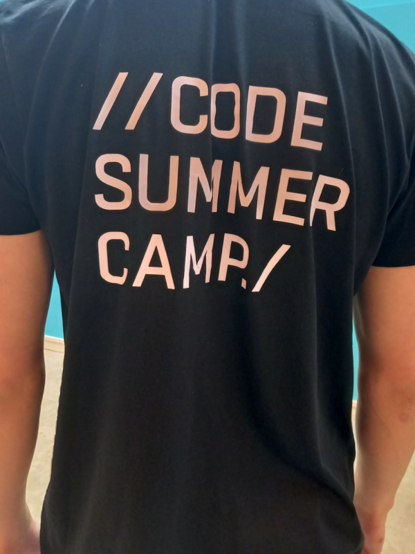 Ryggen på en person med texten Code Summer Camp på träjan