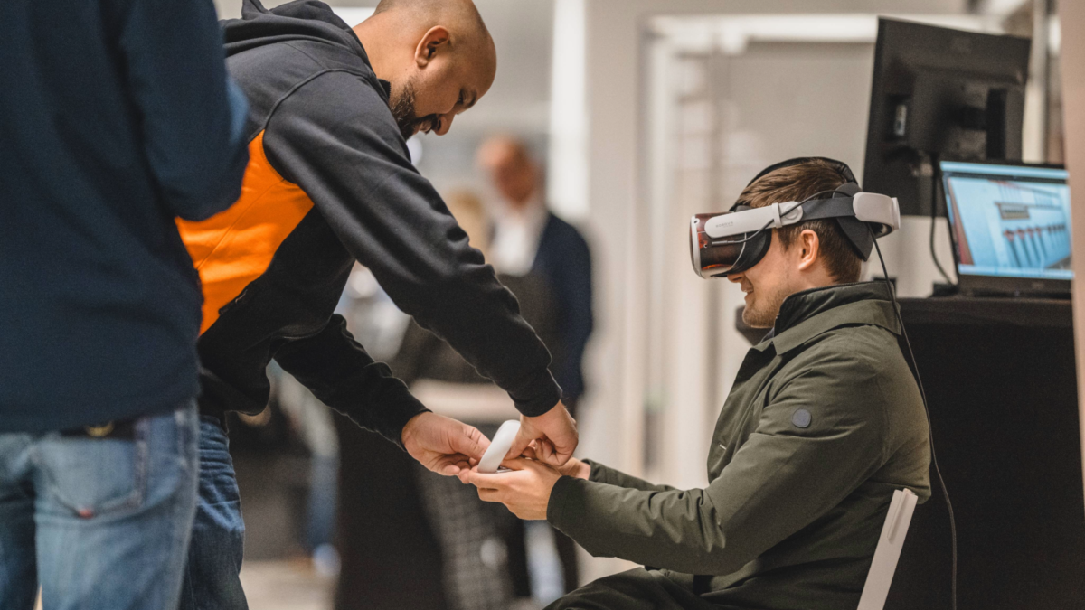 En uman som visar en besökare hur VR-glasögon fungerar.