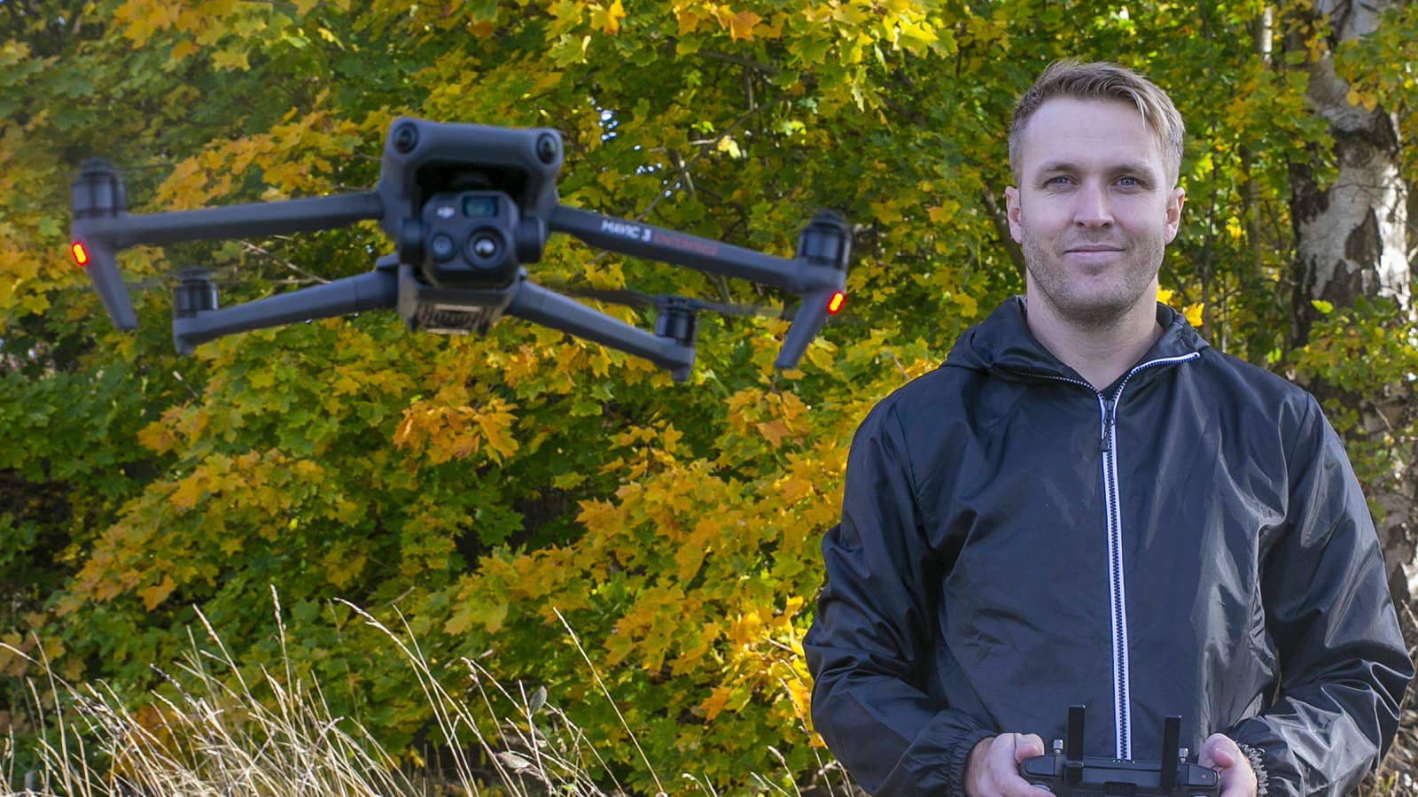 Viktor från Ajaxon Consulting som står brevid en drönare som han styr via en kontroll.